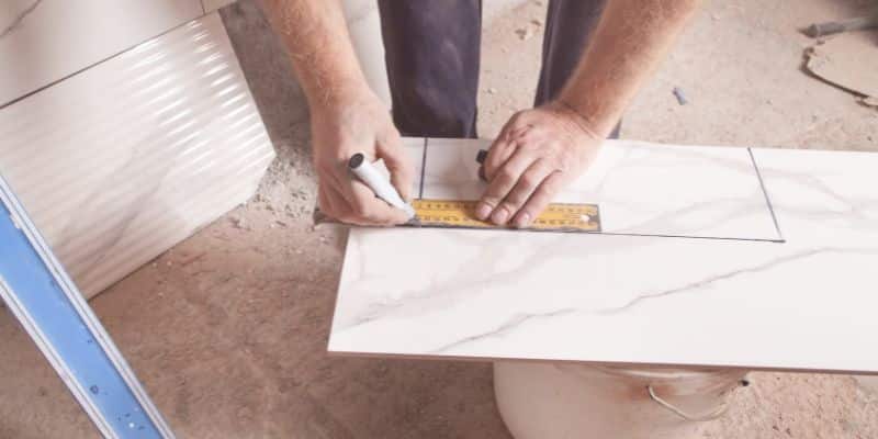 Person measuring a tile with a ruler